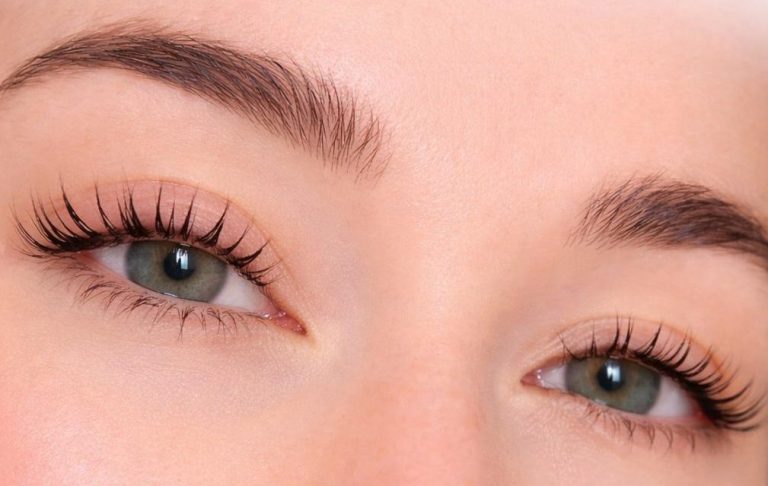 Nahaufnahme eines Gesichts mit grünen Augen und langen Wimpern.